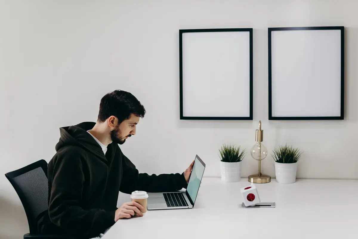 Freelancer working on his laptop while holding a coffee