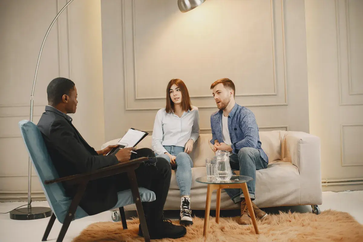 Broker in blacksuit talking to couple