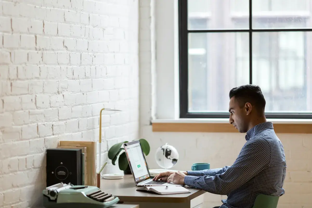 Broker sitting on green chair while using laptop