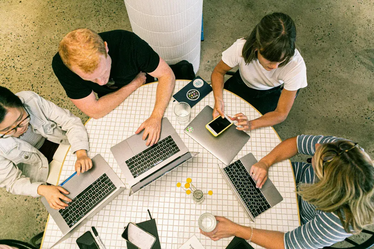 Four people using laptop while talking about mortgage broker