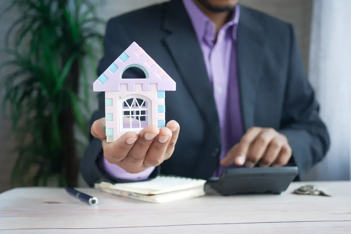 Agent holding a small wooden house
