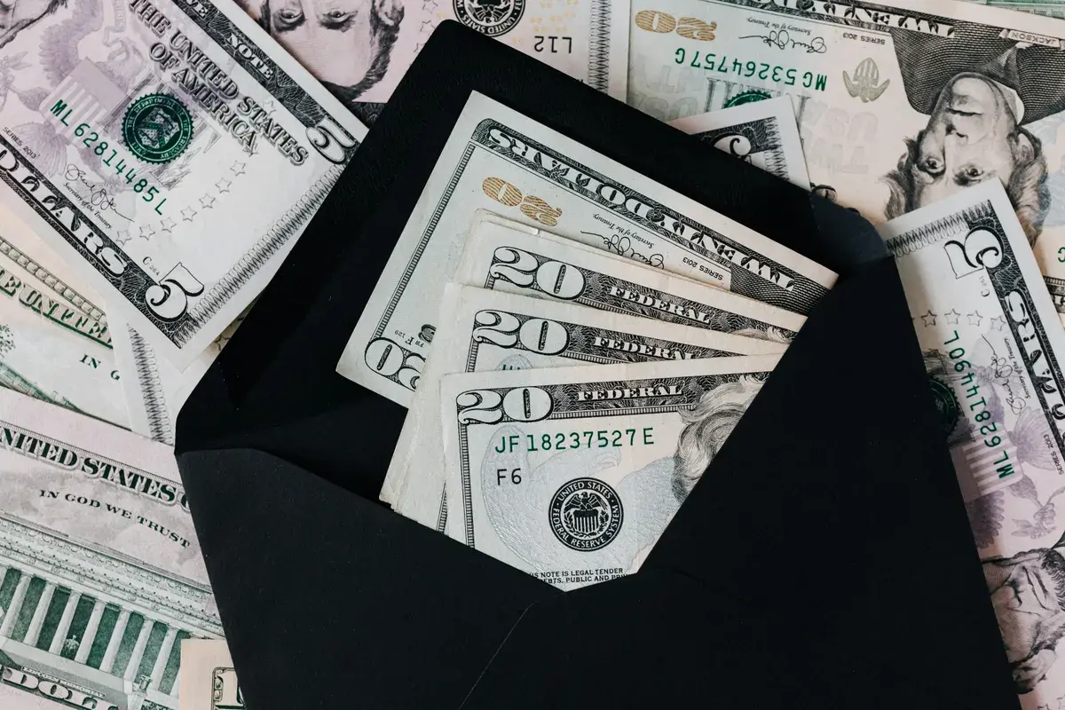 Black opened envelope and cash dollars