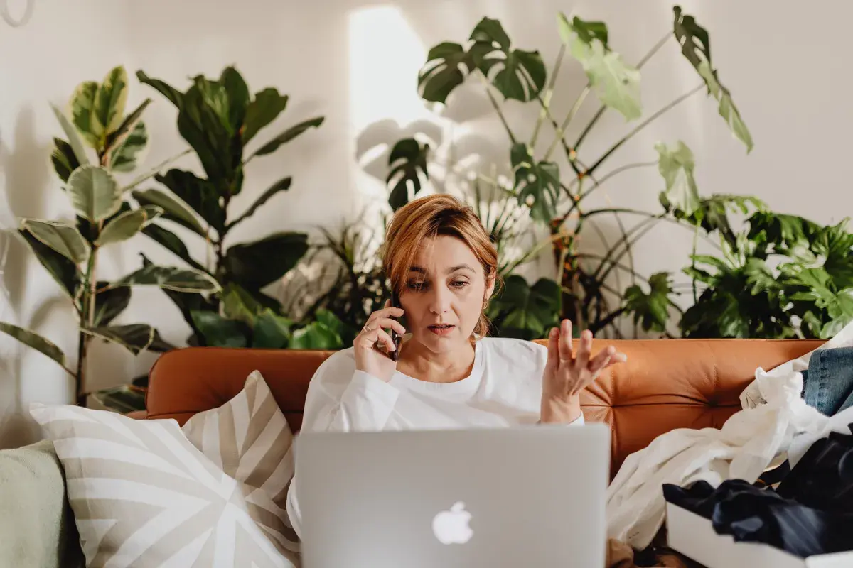 Woman talking on the phone while a laptop is on her lap